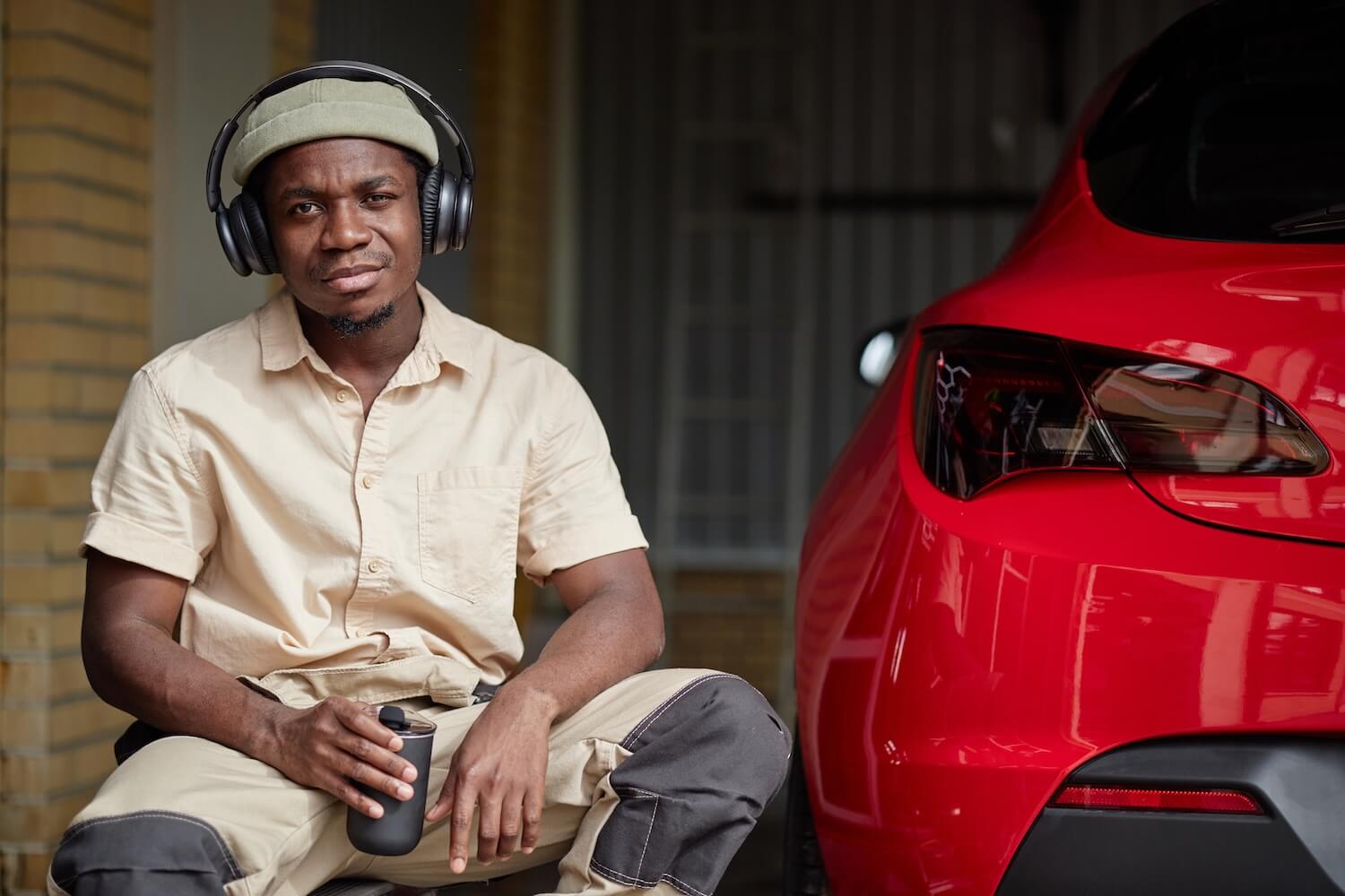 Man With Headphones Poses Near Red Car